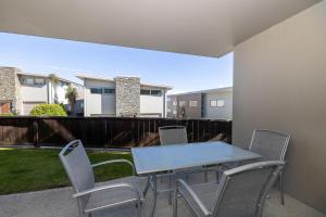 a table and chairs on a patio with a balcony at Cosy Alpine Retreat in Wanaka