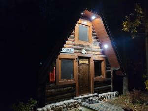 a log cabin with a wooden door at night at Klimatyczne Domki - Całoroczne in Radomsko
