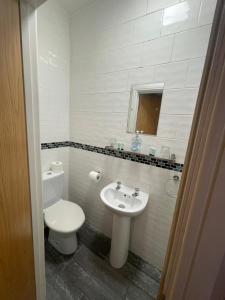 a white bathroom with a toilet and a sink at Abbey Guest House in Milton Keynes