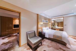 una camera con letto, sedia e specchio di Yinchuan Xifujing Hotel a Yinchuan