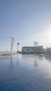 una grande piscina d'acqua con un edificio sullo sfondo di Boss Legian Hotel Powered by Archipelago a Legian