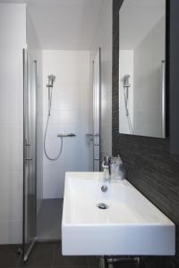 a white bathroom with a sink and a shower at Hostal Emeritae in Mérida