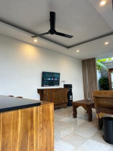 a living room with a ceiling fan and a tv at Gyanesh Villa in Ubud