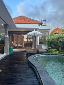 a house with a swimming pool and an umbrella at Gyanesh Villa in Ubud
