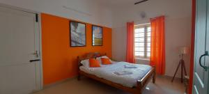 a bedroom with orange walls and a bed with orange pillows at Orange Valley Homestay Trivandrum in Trivandrum