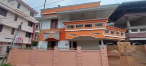 un bâtiment orange avec une clôture devant lui dans l'établissement Orange Valley Homestay Trivandrum, à Trivandrum