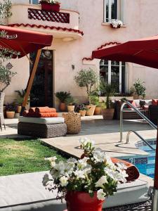un patio con piscina, sombrilla roja y flores en Villa Maskali en Cuxac-dʼAude