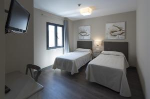 a room with two beds and a flat screen tv at Hostal Emeritae in Mérida