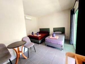 a room with two beds and a table and chairs at Davy Cottage Phuket in Ban Riang
