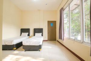 duas camas num quarto de hospital com uma janela em Athena Syariah Residence em Tangerang