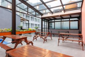un patio con mesas de madera y bancos en un edificio en Sans Hotel Suryakencana Bogor, en Bogor