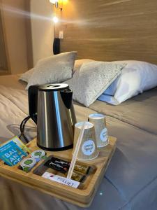 a tray with a coffee pot on top of a bed at Hôtel Du Cheval Blanc in Barcelonnette