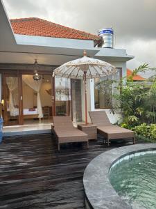 a patio with chairs and an umbrella and a swimming pool at Gyanesh Villa in Ubud