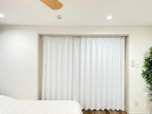 D2HOTEL في أوساكا: غرفة نوم مع نافذة كبيرة مع ستائر بيضاء