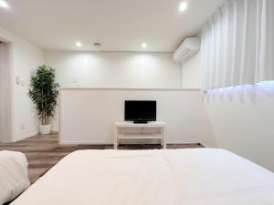 ein Schlafzimmer mit einem Bett und einem TV auf einem Tisch in der Unterkunft D2HOTEL in Osaka
