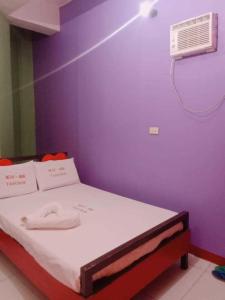 a bed in a room with a purple wall at WJV INN TABUNOK in Talisay