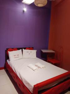 a bed with two white pillows and a purple wall at WJV INN TABUNOK in Talisay