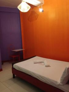 a bedroom with a bed with an orange wall at WJV INN TABUNOK in Talisay