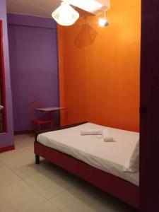 a bed in a room with a purple and orange wall at WJV INN TABUNOK in Talisay