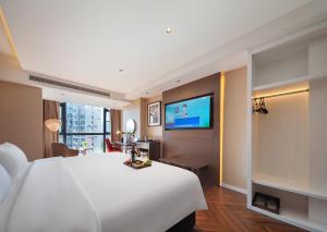 a hotel room with a large bed and a flat screen tv at Zhangjiajie Metropolo Hotel in Zhangjiajie