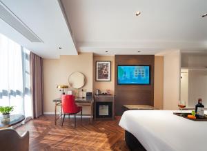 Habitación de hotel con cama, escritorio y TV. en Zhangjiajie Metropolo Hotel en Zhangjiajie