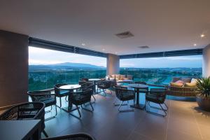 a restaurant with tables and chairs and a large window at Impiana Hotel Senai in Kulai