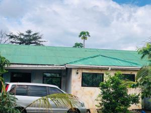 Kilibase Hotel في موشي: سيارة متوقفة أمام منزل بسقف أخضر