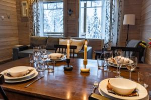 a dining room with a table with plates and candles at Holiday in Lapland - Ellenpolku 2 K2 in Ylläs