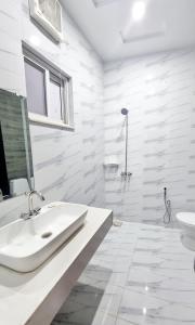 a white bathroom with a sink and a toilet at Hotel Grand Pakeeza in Lahore