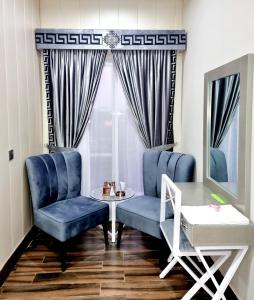 拉合爾的住宿－Hotel Grand Pakeeza，一间设有蓝色椅子、一张桌子和窗户的房间