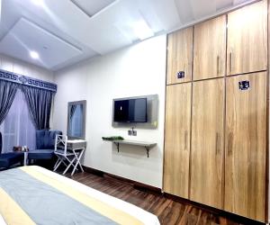 a bedroom with a bed and a tv and cabinets at Hotel Grand Pakeeza in Lahore