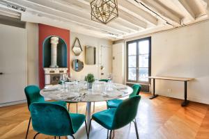 ein Esszimmer mit einem Tisch und grünen Stühlen in der Unterkunft Le Marais Superb Apartment Terrace Paris in Paris