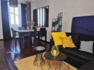 a living room with a black couch and a table at Agréable maison de ville, en triplex in Blois