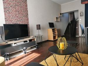 a living room with a flat screen tv and a table at Agréable maison de ville, en triplex in Blois