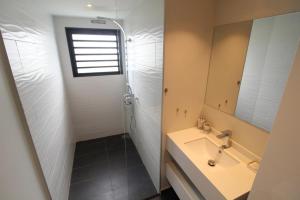 ein Bad mit einem Waschbecken und einer Dusche in der Unterkunft Heiata Sky apartment 3 bedr in Papeete pool & gym garden Wi-Fi Netflix in Papeete