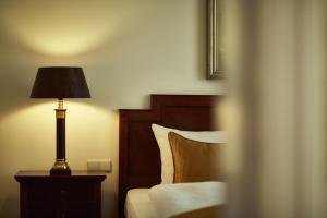 ギュータースローにあるパークホテル ギュータースローのベッドルーム1室(ベッド1台、テーブルの上にランプ付)