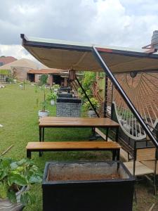 eine Reihe von Picknickbänken in einem Garten in der Unterkunft MANOVA BOUTIQUE HOTEL KIGALI in Kigali