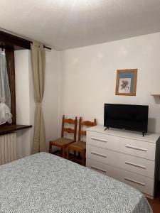バルドネッキアにあるAppartamento Bardonecchiaのベッドルーム(ベッド1台、ドレッサー内のテレビ付)