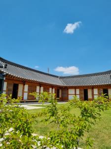 um edifício com um telhado preto e algumas árvores em Wonhwaroo em Gyeongju