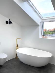 a bathroom with a large white tub and a window at House in beautiful Copenhagen in Copenhagen