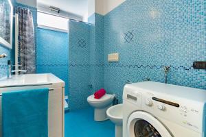 a blue bathroom with a washing machine in it at Appartamento L'Approdo Trilo Rosso - MyHo Casa in Marina di Montenero +2 photos