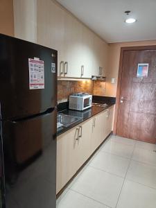馬尼拉的住宿－釃爾公寓，厨房配有黑色冰箱和微波炉。
