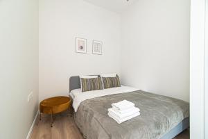 a white bedroom with a bed and a wooden chair at New & Stylish Old Town Apartment by URBAN RENT in Vilnius