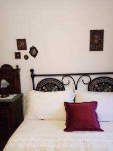 a bedroom with a bed with white sheets and red pillows at Podere Battegone in Menestrello +53 photos