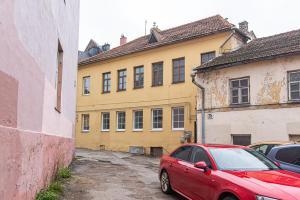 a red car parked in front of a yellow building at New & Stylish Old Town Apartment by URBAN RENT in Vilnius