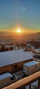 DurtolにあるGîte des Puys - Pinatelle - Durtolの日没を背景にした建物の雪屋根