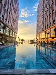 une grande piscine entre deux grands bâtiments dans l'établissement Apec Mui Ne sea view apartment, à Ấp Thiẹn Ái