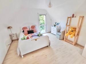 um quarto com uma cama branca e um urso de peluche em LA KERVAO - Villa 5 chambres - Jardin - Terrasse - Internet em Quimper