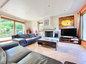 een woonkamer met een bank en een flatscreen-tv bij LA KERVAO - Villa 5 chambres - Jardin - Terrasse - Internet in Quimper