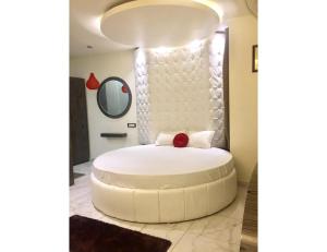 een groot wit bed in een kamer met een spiegel bij Hotel The Royal, Sehore in Sehore